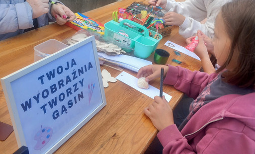 Dzieci uczestniczą w warsztatach plastycznych na stoisku Książnicy Pruszkowskiej podczas sąsiedzkiego spotkania na Gąsinie.