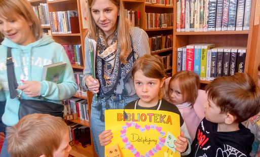 Dzieci z Przedszkola Miejskiego nr 1 w Pruszkowie wręczają bibliotekarkom własnoręcznie wykonaną laurkę w podziękowaniu za lekcję biblioteczną.